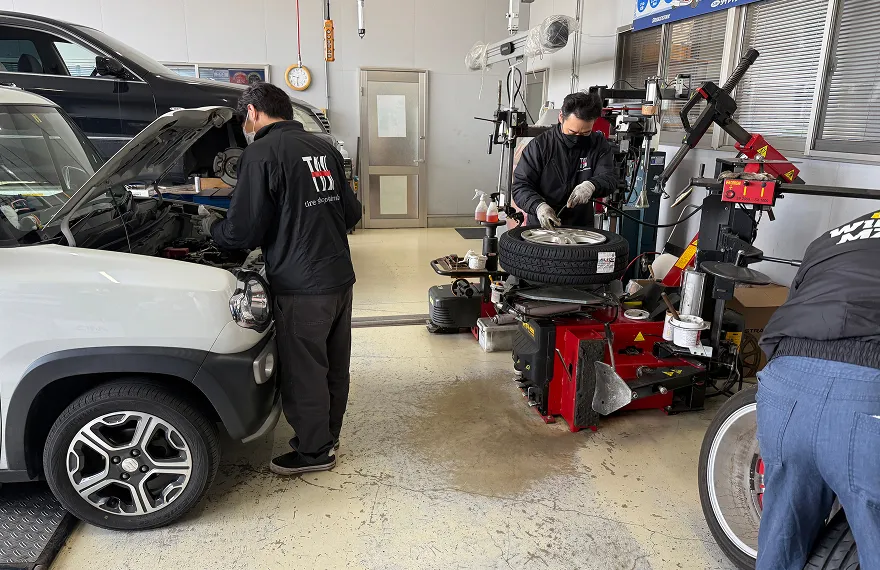 整備工場でタイヤ交換とエンジン点検を同時に行う作業スタッフたち