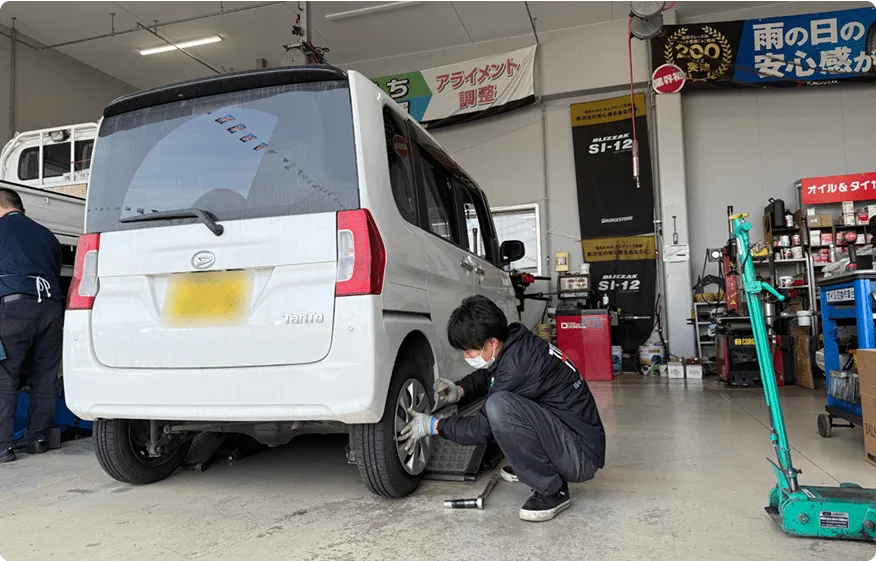 軽自動車のタイヤ交換を行う整備士の作業風景